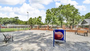A playground with a blue and red ball, a swing set, and a bench.